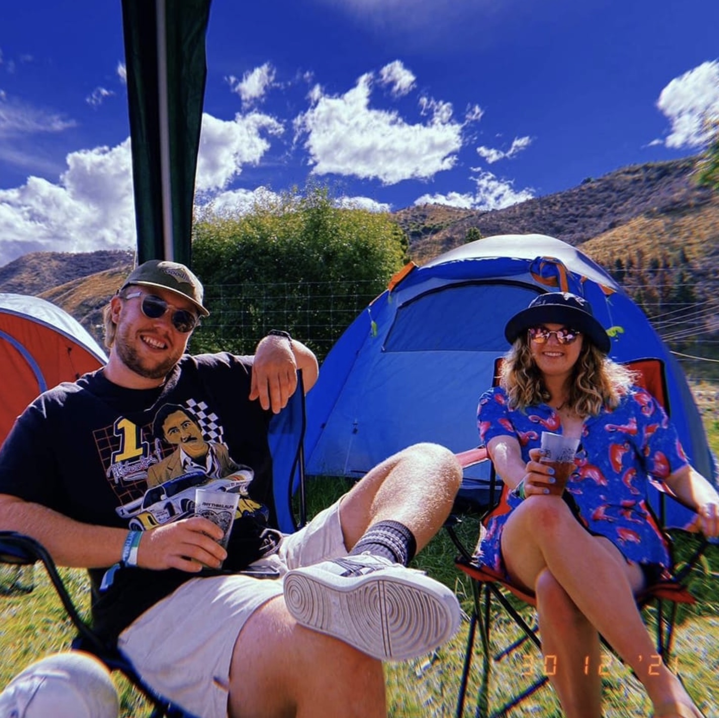 Two people relaxing at a campsite in the sun.